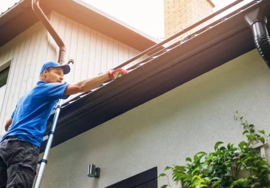 A man cleaning the gutters of a house.